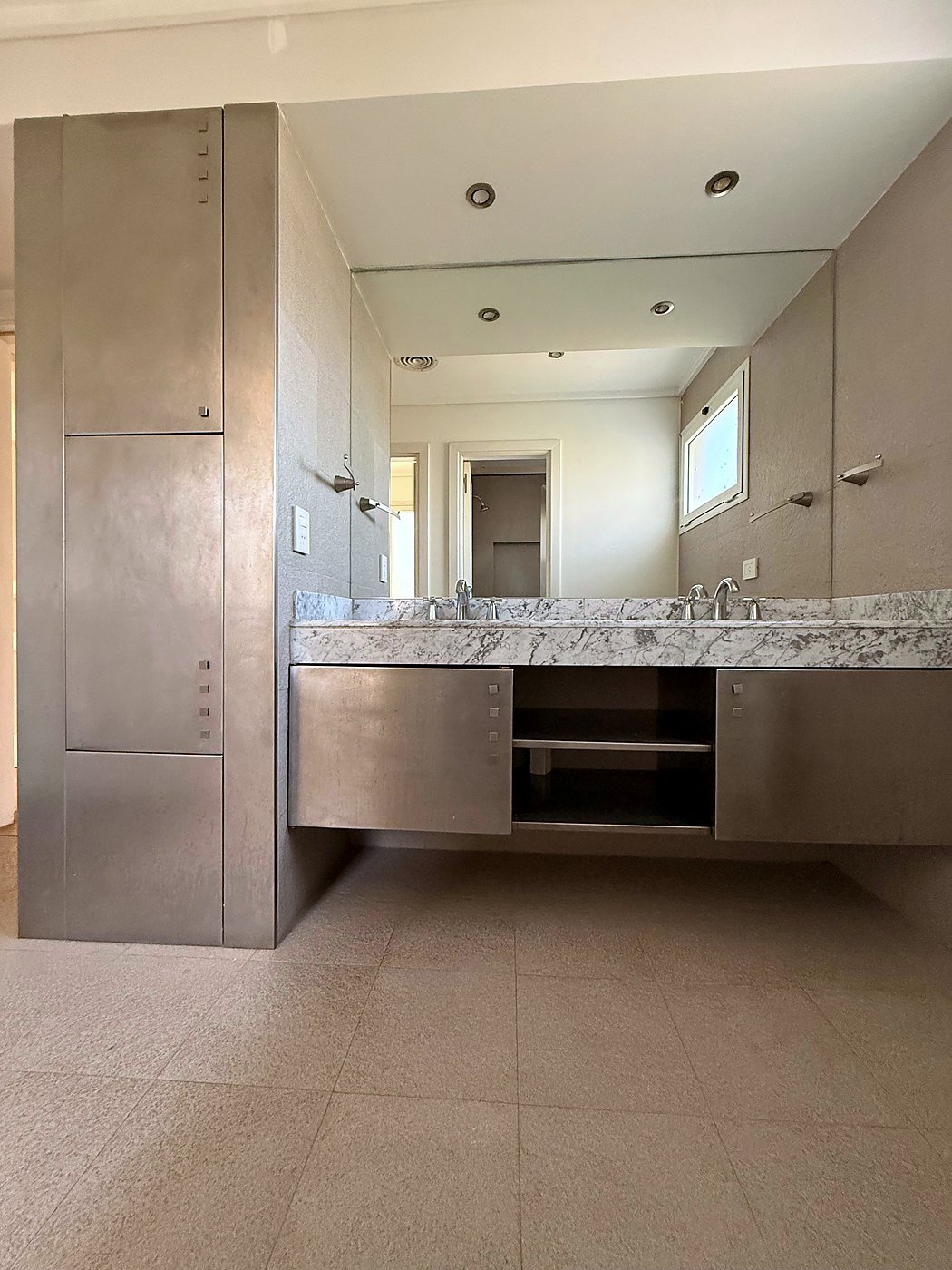 Primary bathroom with double vanity, marble counter, floating metal cabinets and full-width mirror