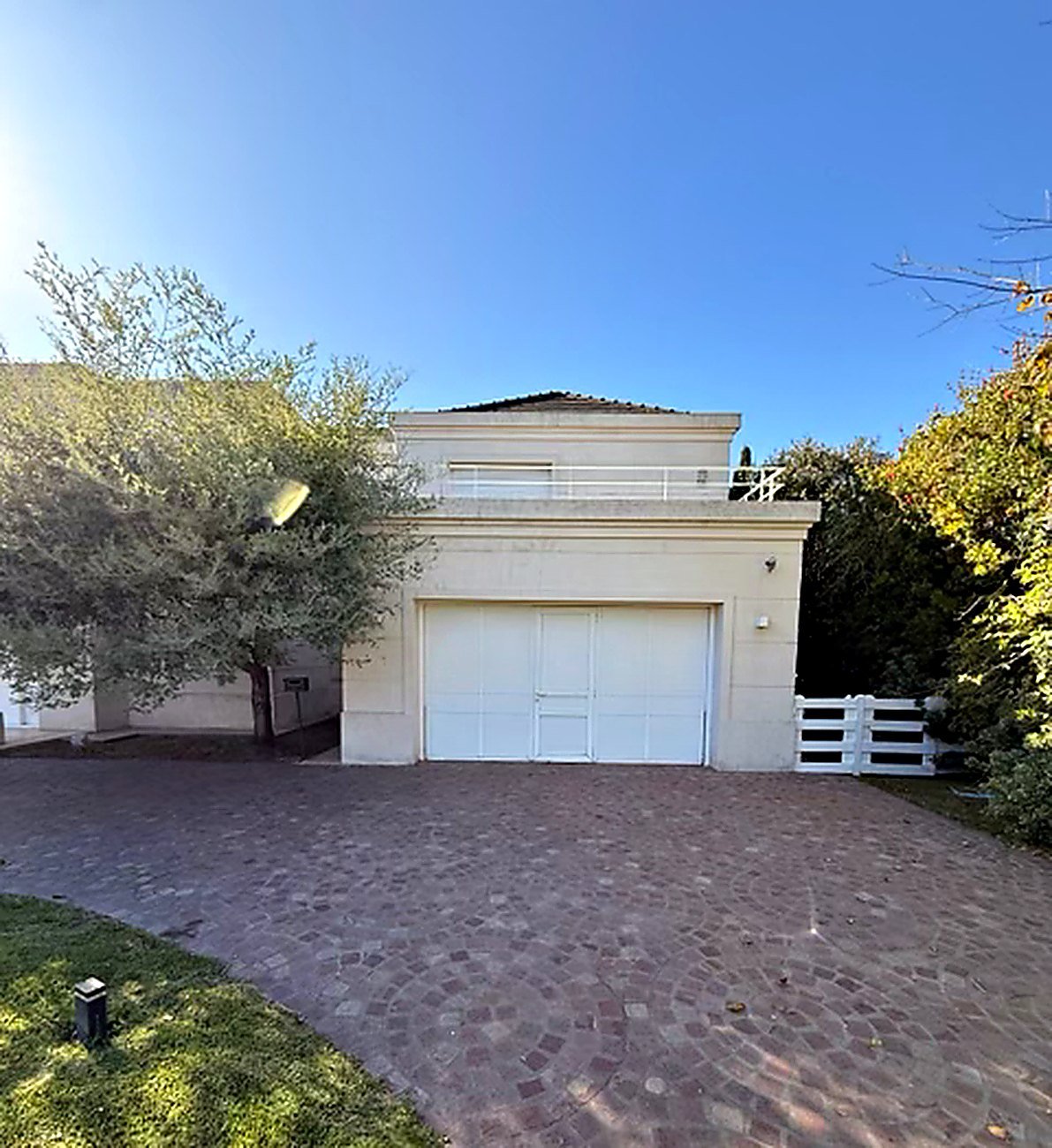 Brick paver driveway leading to the garage below a first-floor terrace at the Funes villa
